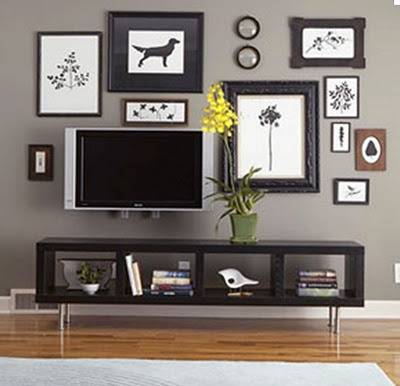 Several black and white paintings hanging over a TV.