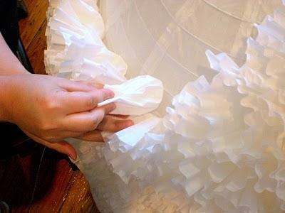 A hand placing white ruffles on a lamp shade