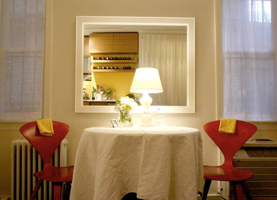 Light lamp on dining table with two red chairs.