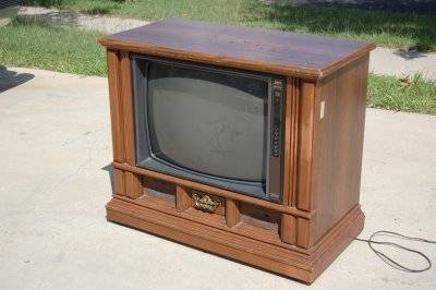 An Old, dirty box TV has a wooden frame.
