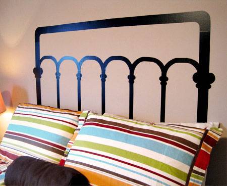 A bed with a fake headboard painted onto the wall.