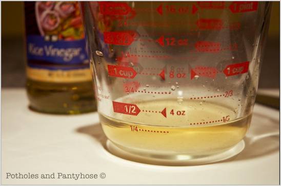 The measuring cup and vinegar bottle is on the table.