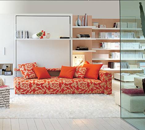 An orange and white sofa sits in a room full of book shelves.