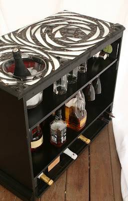 A black, swirly shelf has alcohol on it.