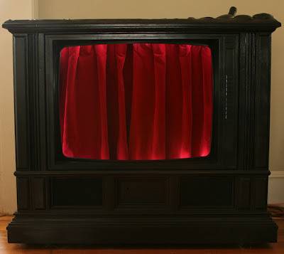 A black piece of furniture with a red curtain on it.