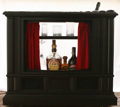 A large black shelf has a red curtain with alcohol glasses on it.