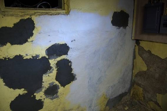 A splotched basement wall with missing paint.