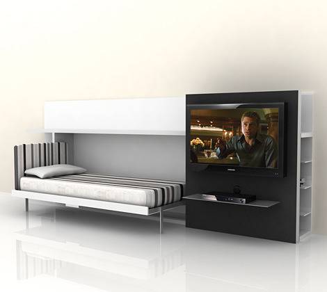 A small bed is sitting near a television mounted on a wall.