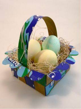 A blue basket of three eggs with hay in it.
