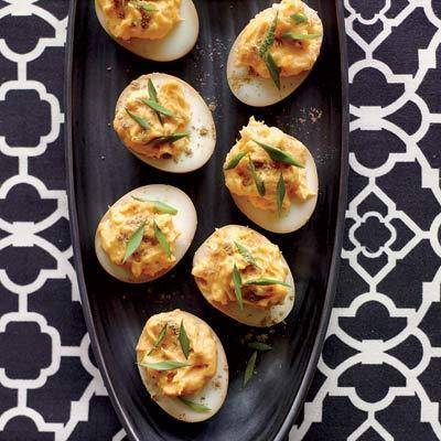 Leftover easter eggs have been turned into deviled eggs and displayed on a dark serving dish.