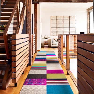 A multi-colored runner near a wooden staircase.