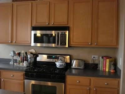 A kitchen has stainless steel and black appliances and ash color wood cabinets.