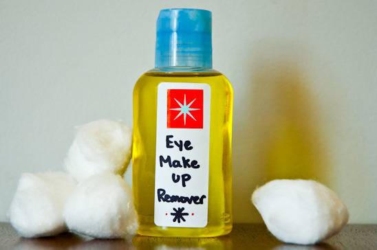 Eye makeup remover bottle and cotton pieces on table.