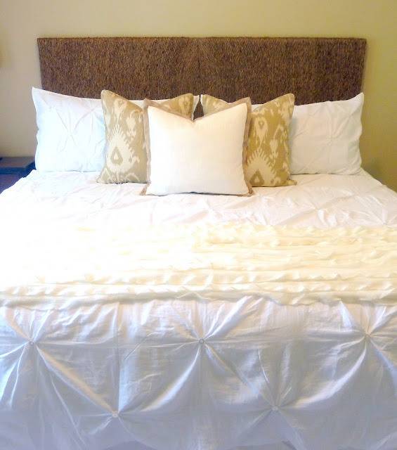 A white bed has a tan headboard.