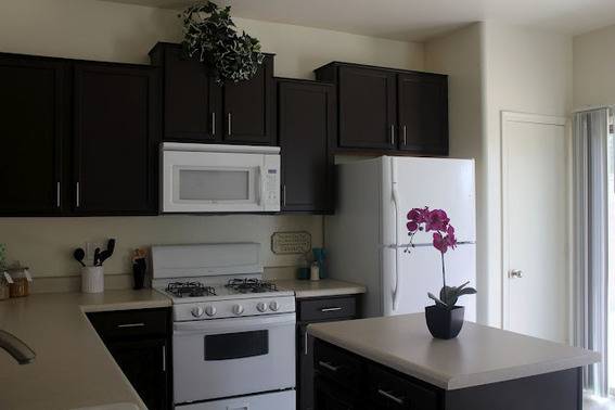 A pink orchid sits on a countertop in front of several dark brown cabinets.