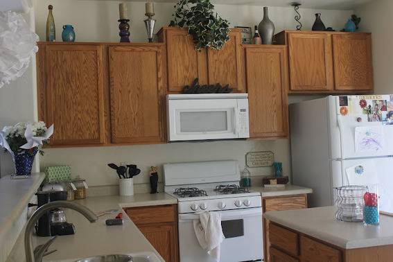 A kitchen having white microwave, Stove, refrigerator and wooden cabinets.