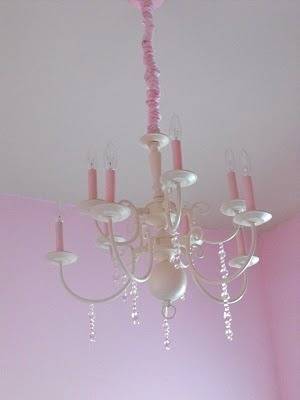 A six arm chandelier with pink candle style lights and a pink cord.