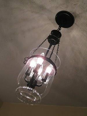 A hanging light with four electric candles in it.