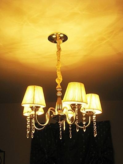 A fifties style chandelier with lampbshades on 5 lamps softly lights a room.