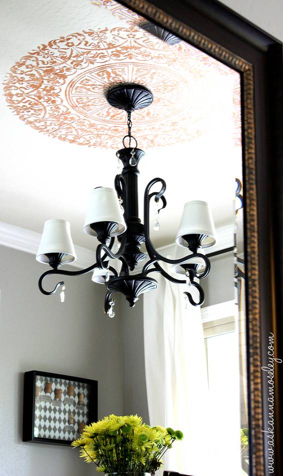 A black chandelier hangs atop a gray room.