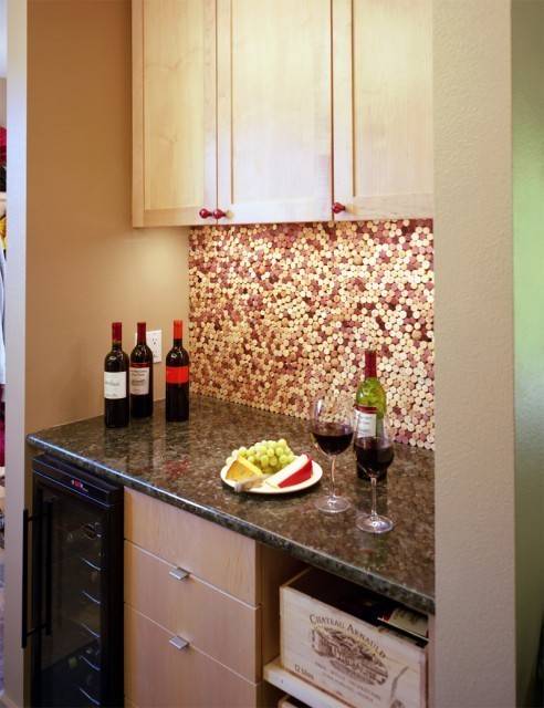 Cabinet counter top with backslash and drink bottles and food items on plate on top.