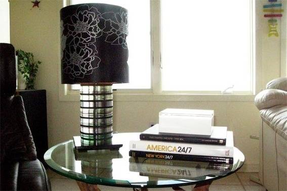 A black and white lamp sits on a glass table near a stack of books.