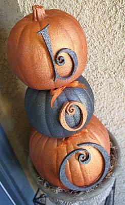 Three pumpkins stacked on top of each other painted orange and black.