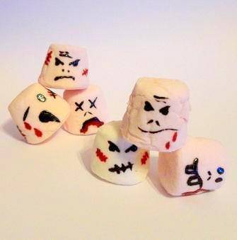Several marshmallows with ghost imagery painted on them.