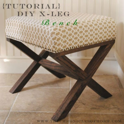 A very small wooden bench or stool has a thick cushion top.