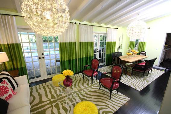 A fully decorated room with white and green curtains and wooden tables and maroon and yellow chairs.