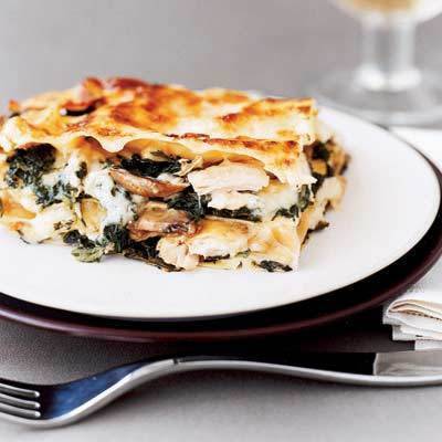 A piece of cheesy chicken layered food sits on a small plate.