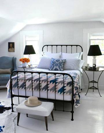 A bed with blue and white sheets in between two lamps.