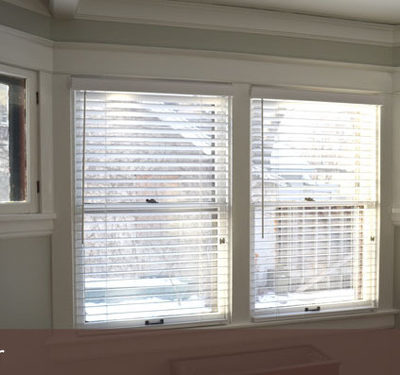 A couple of windows with white blinds.