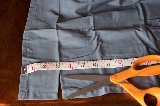 Tape measure across a blue shirt with orange scissors.