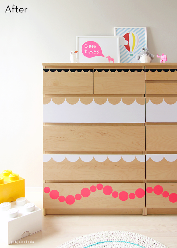 A chest of drawers is colorfully decorated in pink, tan, black, and white in a baby's room.