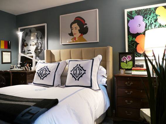 Black and white pillows with monograms on a bed in a room with white walls and artwork.