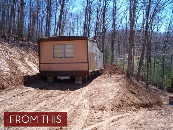 A mobile home sits on supports in a wooded area that has recently been partially cleared for this purpose.