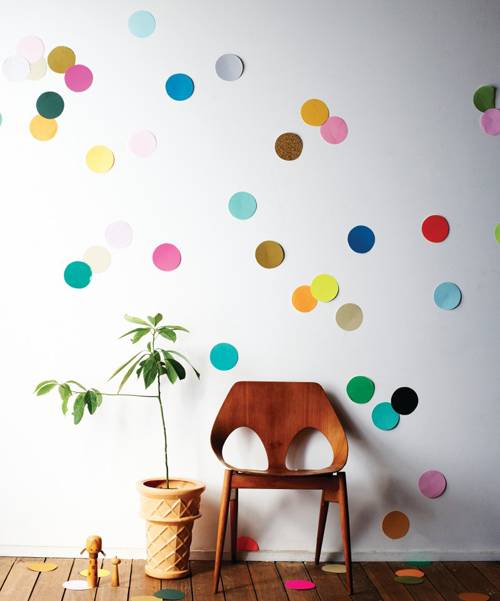 A white wall covered in dots behind a chair.