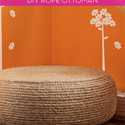 A light brown ottoman is next to an orange wall.