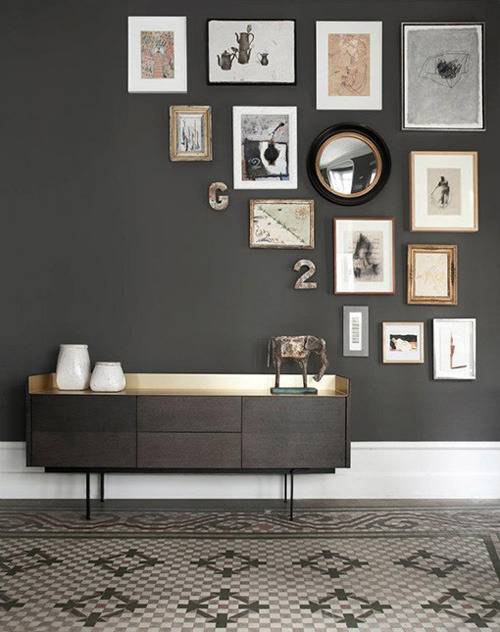 A short grey table in a room with grey walls and pictures on it.