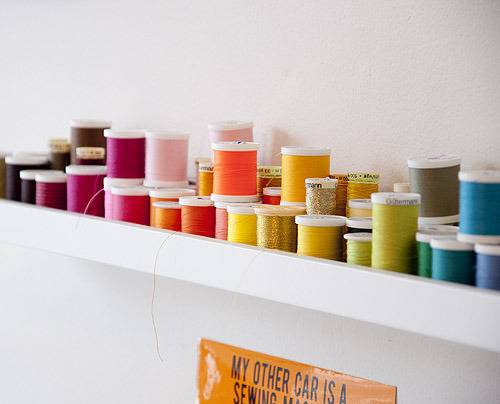 Various colored threads on a wall rack.