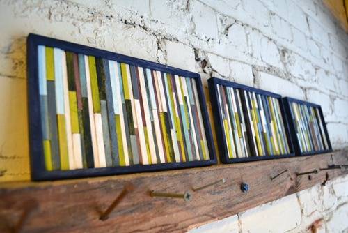 Group of rectangular picture frames with rectangles painted on inside on top of wood shelf.