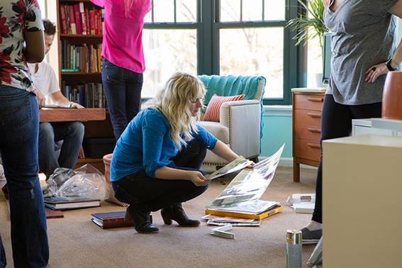 Five people are working with books in a living room.