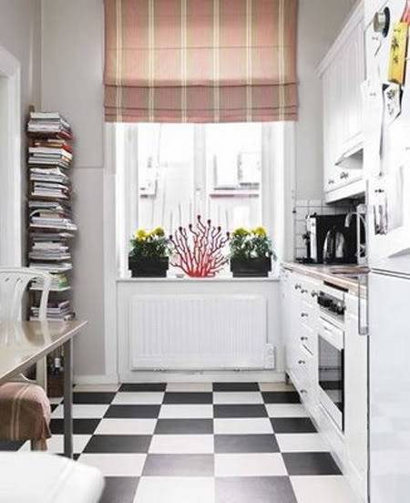 A small room has a black and white checkered floor and a window with flowers on the sill.