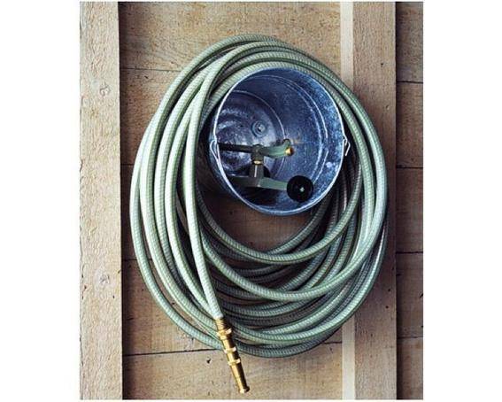 A garden hose coiled around a fixture on a wooden wall.