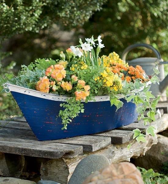 Flowers sit in a blue container on wood slats.