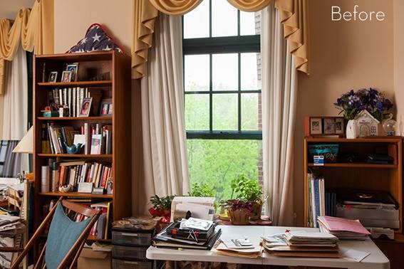 Bookshelves and white table near a green window.