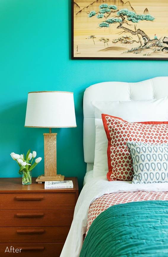 A bed side table with a small plant and a lamp on it next to a bed.