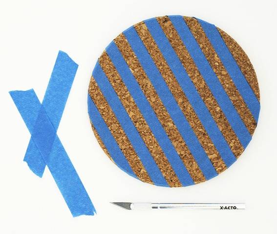 Blue tape is striped on a cork board.