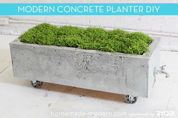 A rectangular concrete planter on wheels has a spigot pointing outward from the planter on one end.